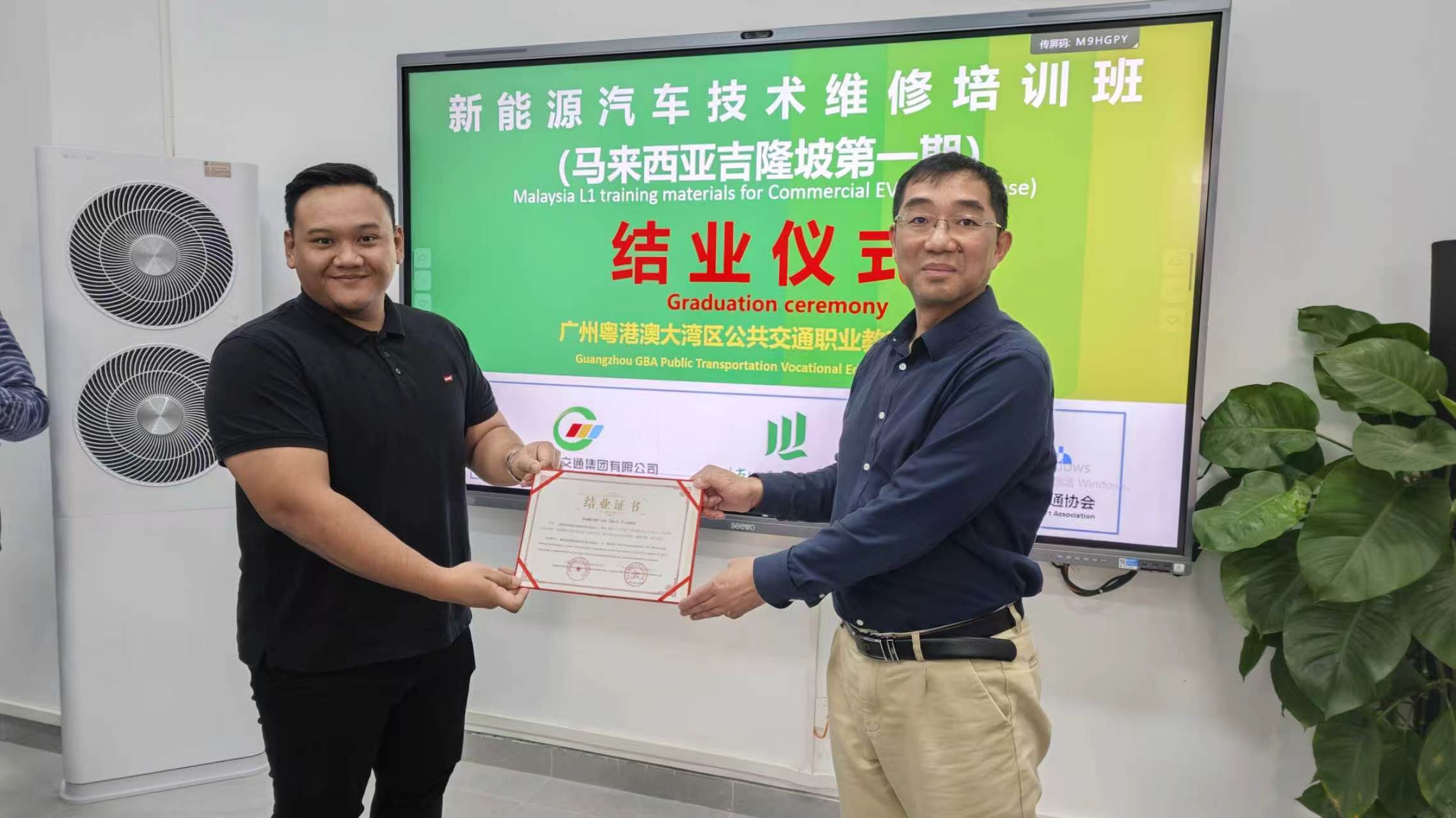 Trainee receiving EV technician completion certificate at graduation ceremony, Guangzhou