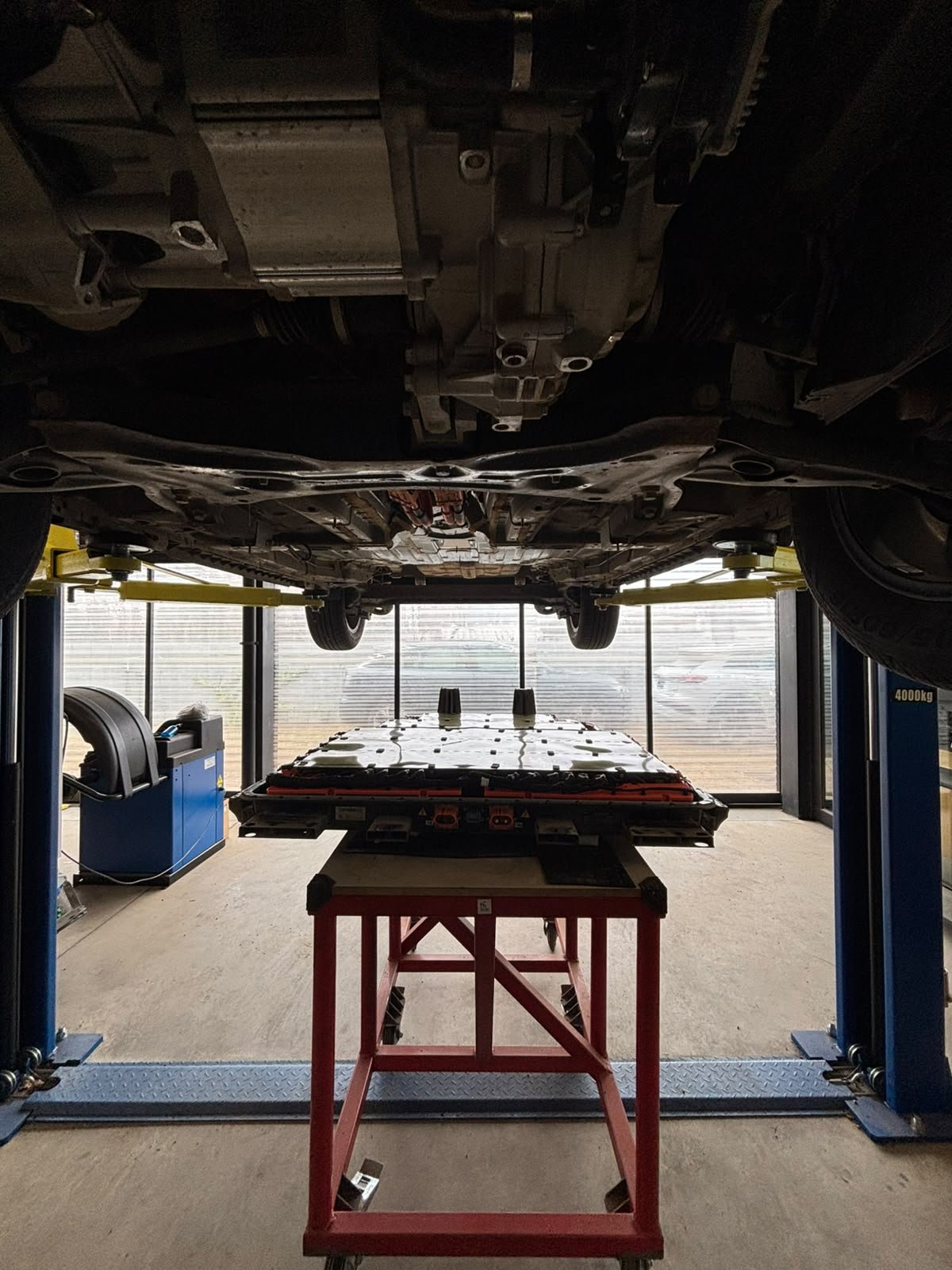 Geely Geometry EV battery pack on hydraulic lift at a professional repair workshop in Uruguay. The workshop contacted NEV Fix for remote battery repair support.